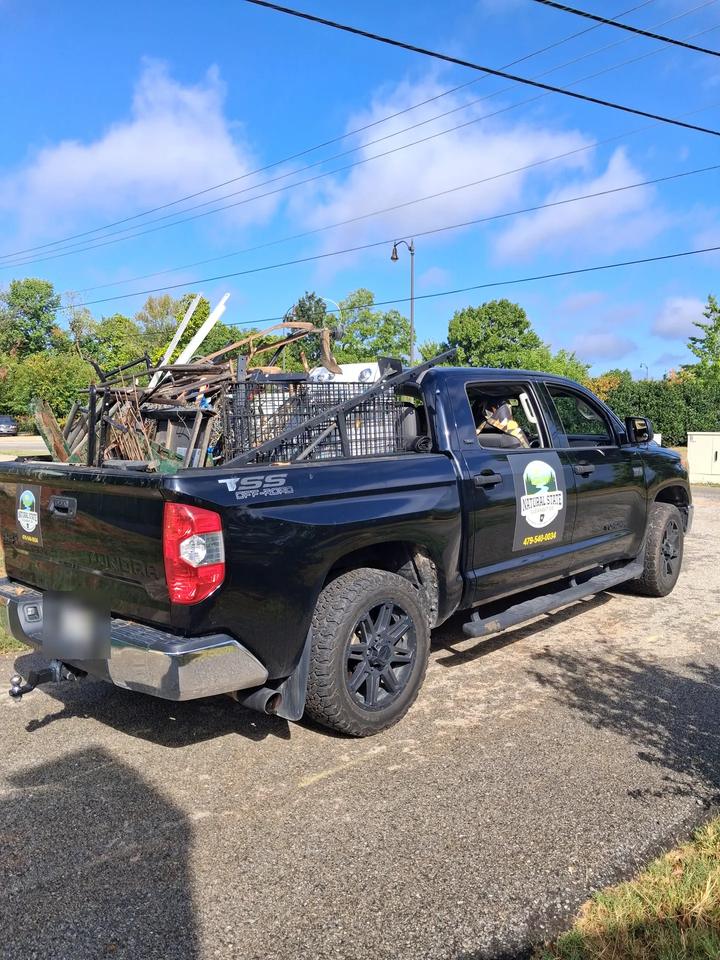 The Natural State Cleanout Co. truck with the bed piled high with scrap metal, a wire cage and old fencing